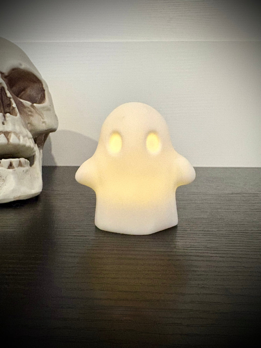 Ghost votive cover glowing with warm amber light through hollow eyes