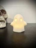 Ghost votive cover glowing with warm amber light through hollow eyes