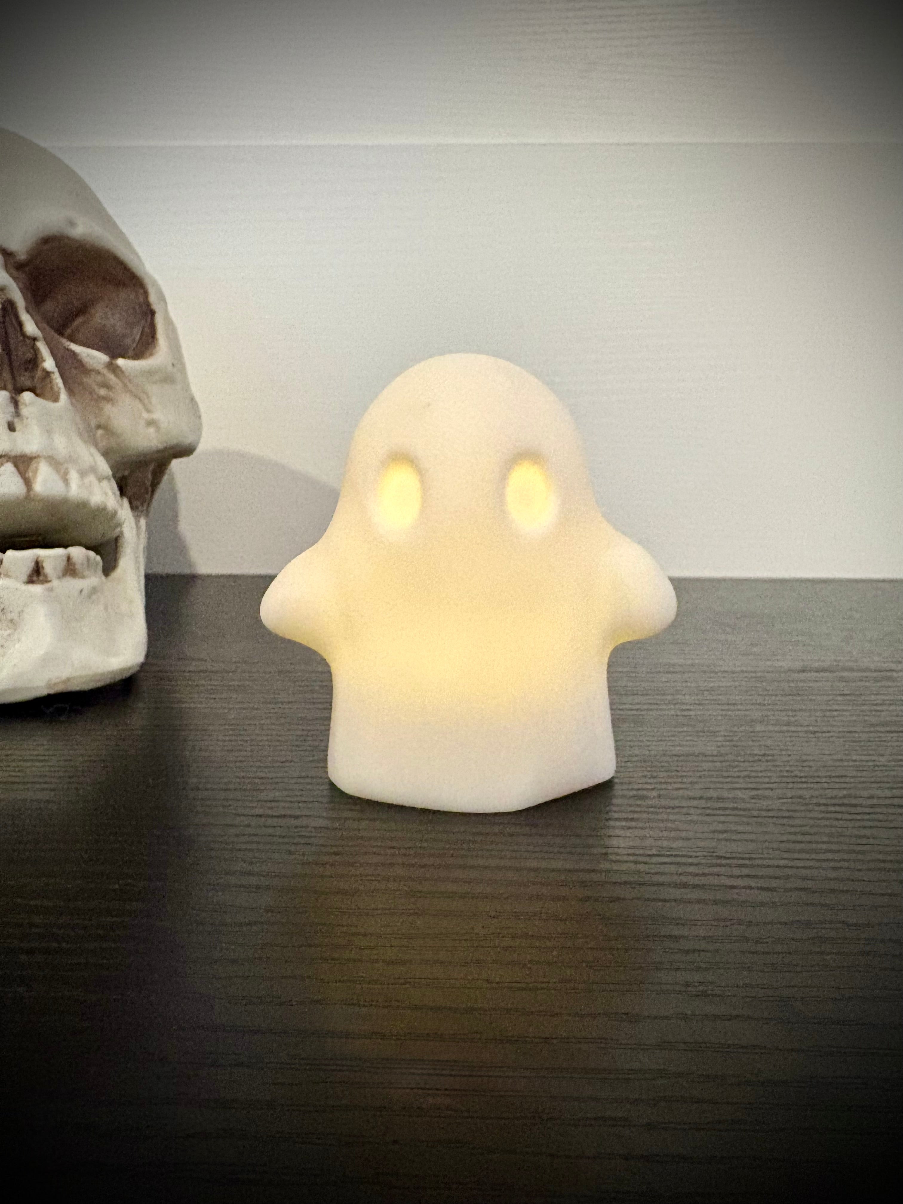 Ghost votive cover glowing with warm amber light through hollow eyes