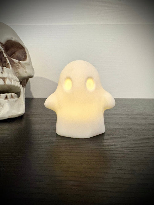 Ghost votive cover glowing with warm amber light through hollow eyes