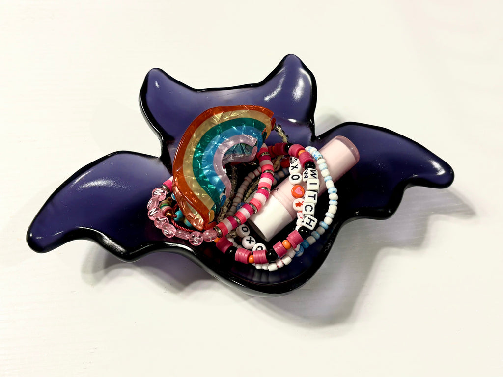 Purple bat-shaped resin catch-all bowl holding jewelry and accessories